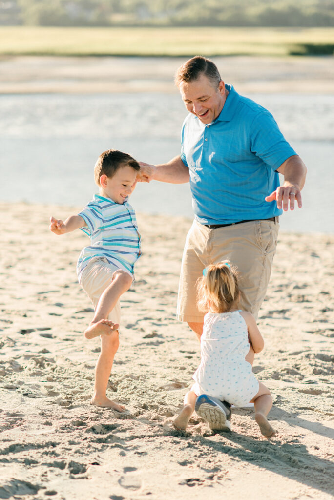 Father playing with kids on a beach in maine